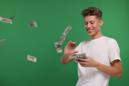 Happy man throwing dollar banknotes on green backgroundの写真素材