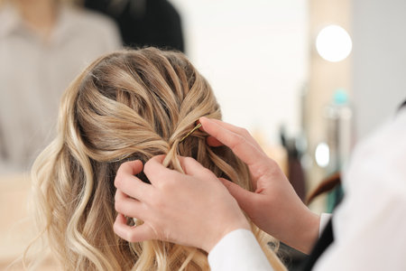 Hair styling. Professional hairdresser working with client in salon, closeup