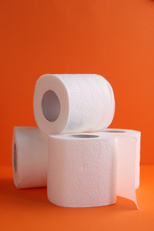 Soft toilet paper rolls on orange background, closeup