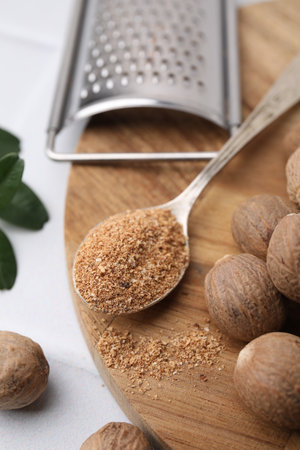 Spoon with grated nutmeg, seeds and grater on white table