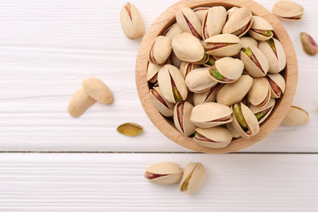 Tasty pistachios in bowl on white wooden table, top view. Space for textの写真素材