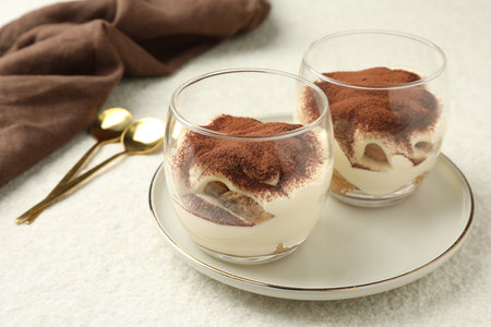 Delicious tiramisu in glasses and spoons on white tableの写真素材