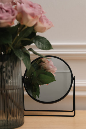Mirror and vase with pink roses on wooden dressing table, closeupの写真素材