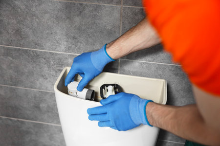 Plumber repairing toilet bowl in water closet, closeupの写真素材