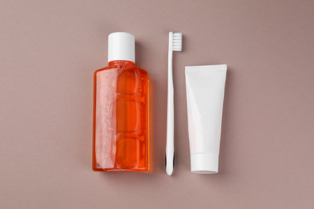 Fresh mouthwash in bottle, toothbrush and toothpaste on beige background, flat layの写真素材