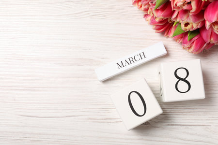 International Women's day - 8th of March. Block calendar and bouquet of beautiful tulips on white wooden table, flat lay. Space for textの写真素材