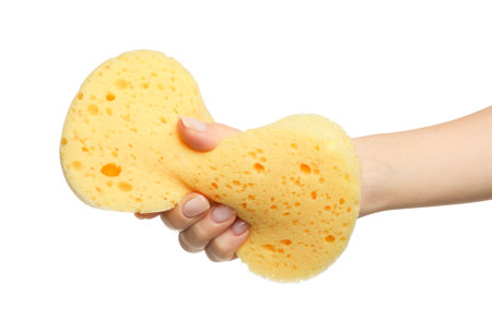 Woman holding new yellow sponge on white background, closeup