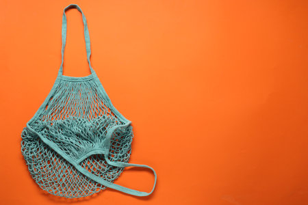 Turquoise net bag on orange background, top view. Space for textの写真素材