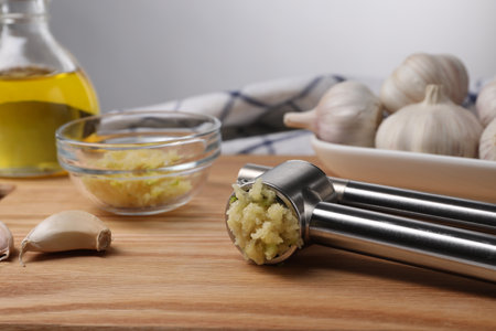 One metal press and garlic on wooden table, closeupの写真素材