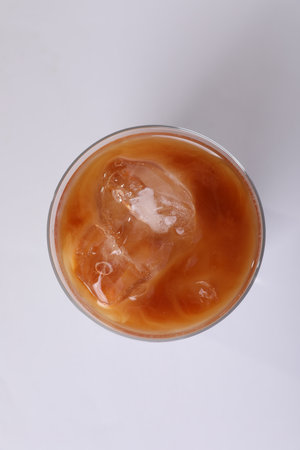 Glass of iced coffee on white table, top view