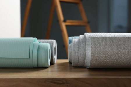 Different wallpaper rolls on wooden table indoors