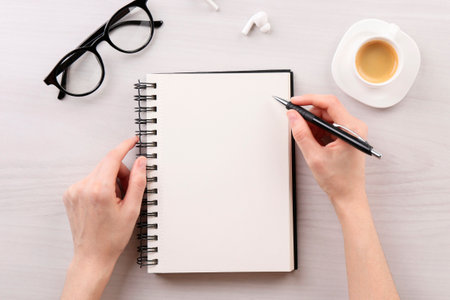 Woman with notebook and pen at white wooden table, top view. Space for textの写真素材