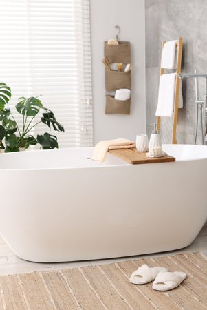 Set of different bath accessories and soap on tub in bathroomの写真素材