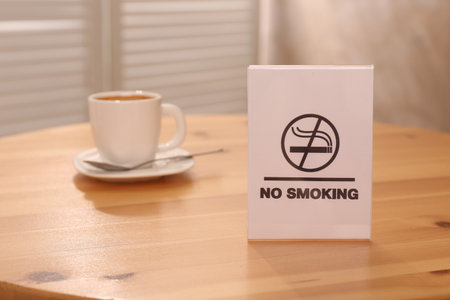 No Smoking sign and cup of drink on wooden table indoors, selective focusの写真素材