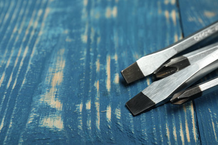Set of screwdrivers on blue wooden table, closeup. Space for text
