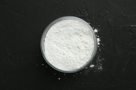 Baking powder in bowl on black textured table, top viewの写真素材