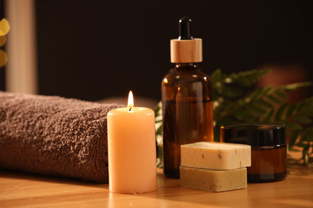Spa composition. Cosmetic products, burning candle and towel on wooden tableの写真素材