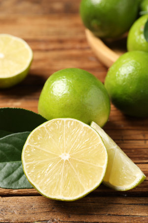 Fresh ripe limes and green leaves on wooden table, closeupの写真素材