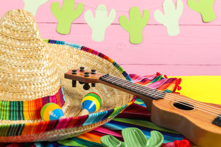 Mexican sombrero hat, ukulele and maracas on yellow table, closeupの写真素材