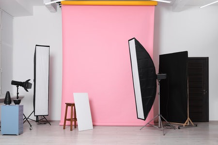 Pink photo background, stool and professional lighting equipment in studioの写真素材