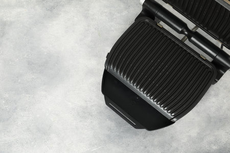 Electric grill on gray textured table, top view. Space for text. Cooking applianceの写真素材