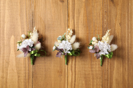 Stylish boutonnieres on wooden table, flat layの写真素材