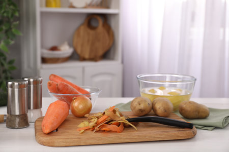 Peels of fresh vegetables and peeler on white wooden table indoorsの写真素材