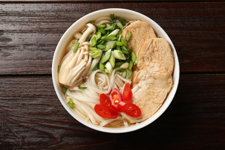 Delicious ramen with meat and mushrooms in bowl on wooden table, top view. Noodle soup