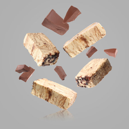 Pieces of tasty halva and chocolate falling on gray backgroundの写真素材
