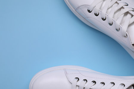 Pair of stylish white sneakers on light blue background, top view. Space for textの写真素材
