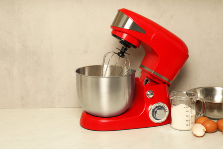 Modern red stand mixer, eggs, container with flour and bowl on white marble table. Space for textの写真素材