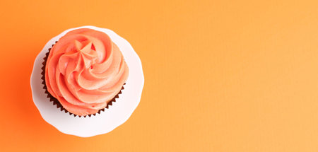 Delicious cupcake with bright cream on orange background, top view. Space for textの写真素材