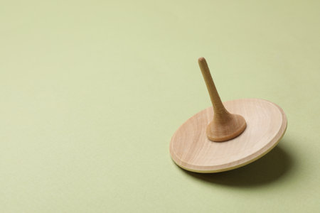 One wooden spinning top on green background, space for textの写真素材