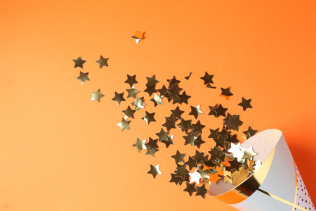 Party hat and confetti on orange background, top viewの写真素材