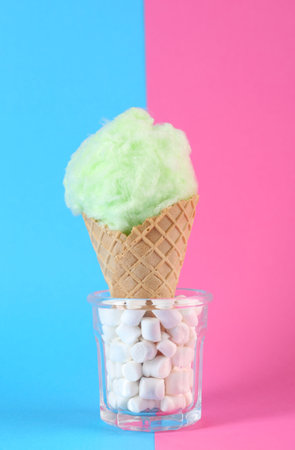 Sweet cotton candy in waffle cone on color backgroundの写真素材
