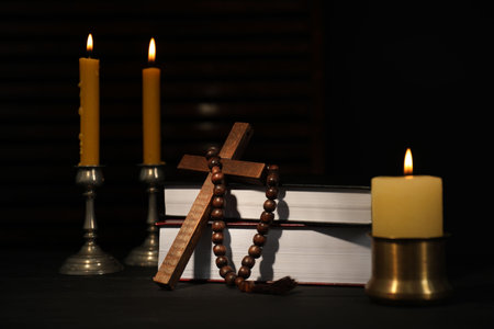 Church candles, Bible, rosary beads and cross on wooden tableの写真素材