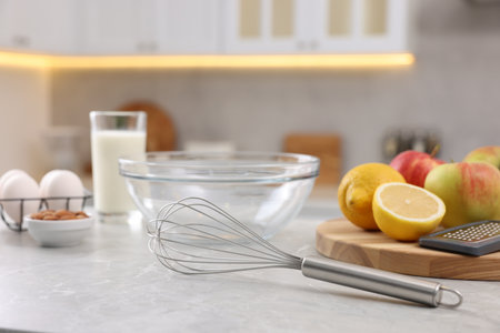 Metal whisk, bowl, grater and different products on gray marble table in kitchenの写真素材