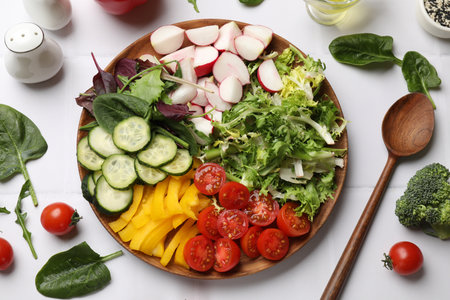 Vegetarian diet. Plate with tasty vegetables and spoon at white tiled table, flat layの写真素材