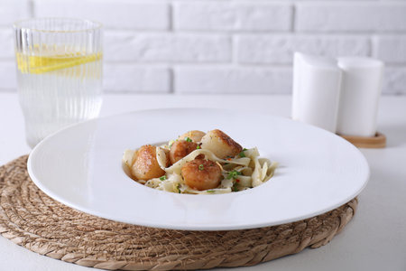 Delicious scallop pasta with spices in bowl on white tableの写真素材