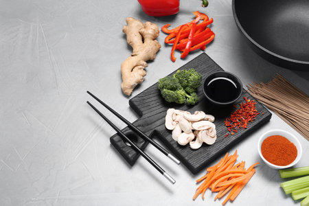 Wok, chopsticks and different products on gray table, space for textの写真素材