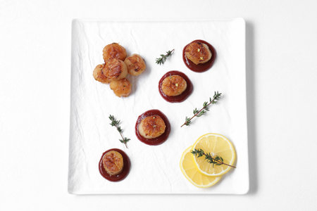 Delicious fried scallops with tomato sauce, thyme and lemon isolated on white, top viewの写真素材