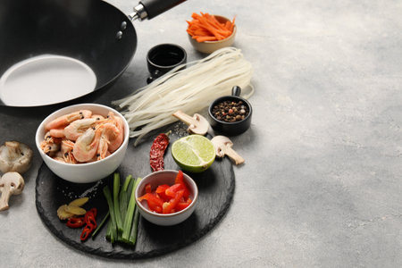 Different products and black wok on gray table, closeup. Space for textの写真素材