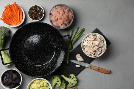 Wok pan, chicken and other products on light gray table, flat layの写真素材