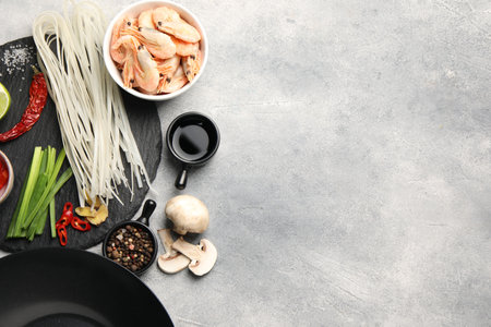 Flat lay composition with black wok, spices and products on gray textured table. Space for textの写真素材
