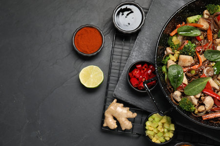 Stir-fry. Tasty noodles with meat in wok and ingredients on gray textured table, flat lay. Space for textの写真素材