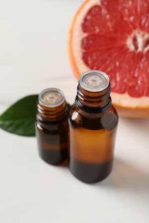 Grapefruit essential oil in bottles, leaf and fruit on white tableの写真素材