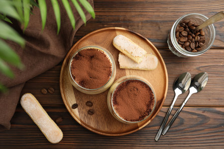 Delicious tiramisu in glasses served on wooden table, flat layの写真素材