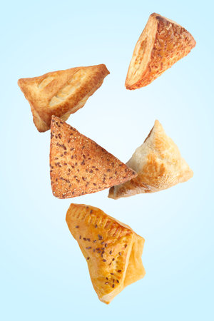 Different tasty puff pastries falling on light blue backgroundの写真素材