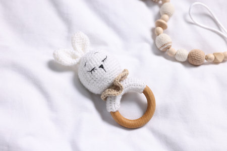 Baby accessories. Rattle and pacifier clip on white fabricの写真素材