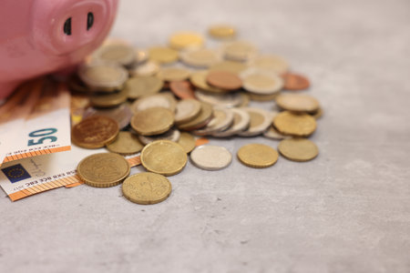 Piggy bank with euro banknotes and coins on gray table, closeup. Space for textの写真素材